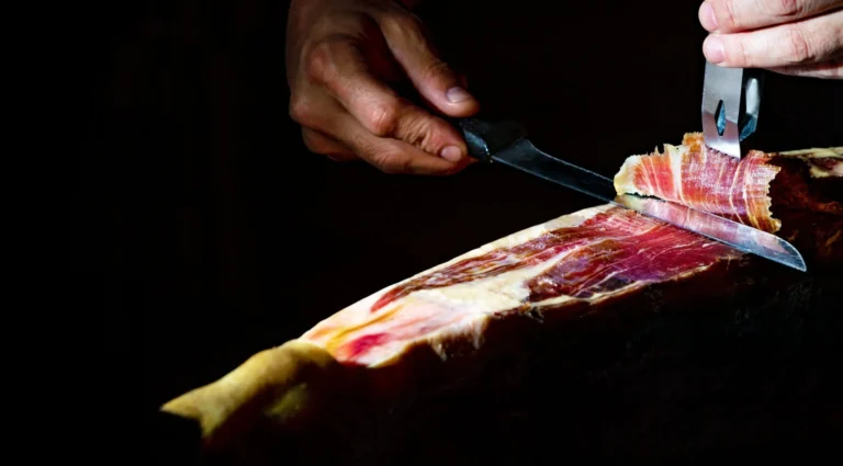 gastronomia-comida-espana-detalle-primer-plano-maestro-cortador-jamon-iberico-sobre-fondo-oscuro-sca